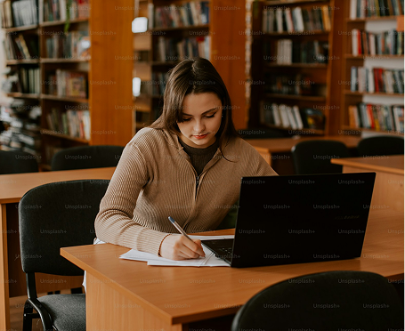 female student working on laptop and sketching on drafting pad